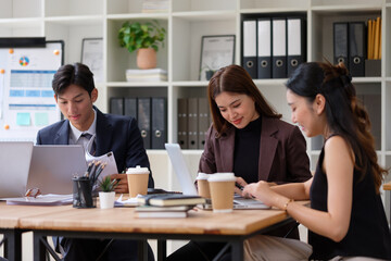 Diverse group of coworkers analyzing data and discussing strategy in modern office.