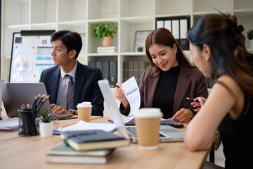 Diverse group of coworkers analyzing data and discussing strategy in modern office.