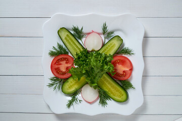 A plate contains a salad with cucumber, tomatoes, and radish. Horizontal shot.