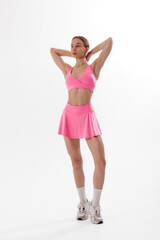 Young woman in pink activewear poses confidently during indoor photo shoot focused on fitness and style