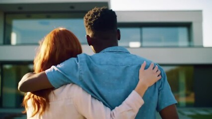 Happy young couple embracing and hugging in front of their big modern house, rearview, celebrating new homeownership, property purchase, dream house, real estate investment and mortgage loan