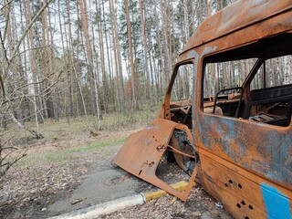 A haunting tableau of rusted, bullet-riddled civilian vehicles stacked in the streets of Irpin,...