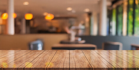 Empty wooden table top with lights bokeh on blur restaurant background.