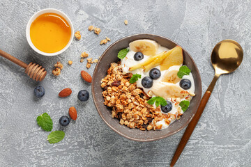 Homemade crispy granola, yogurt, fruits and berries in bowl on table. Healthy breakfast. Top view