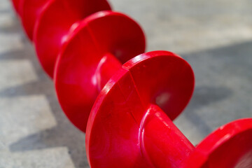 Tarière rouge industrielle posée au sol, utilisée pour le transport mécanique de matériaux en...
