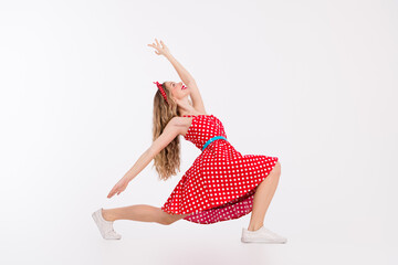 Energetic young woman posing in a retro polka dot dress exudes joy and fun with her cheerful dance...