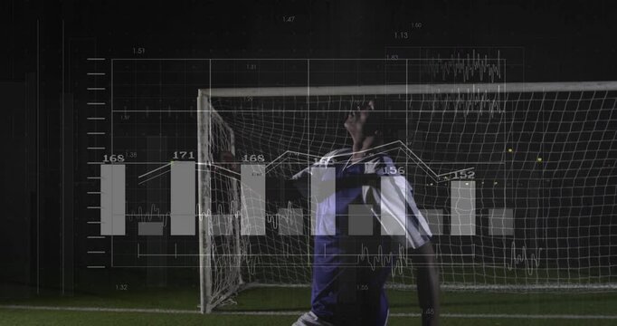 male soccer player raising arms in front of goal at night, showing sports analytics overlays - Powered by Adobe