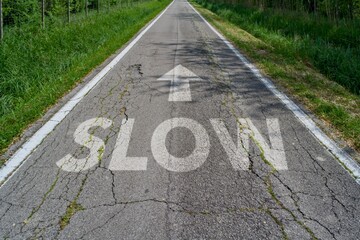 Strada dritta con testo SLOW con freccia sull'asfalto