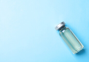 Hepatitis vaccine in glass vial on light blue background, top view. Space for text