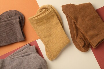 Different soft socks on color background, top view