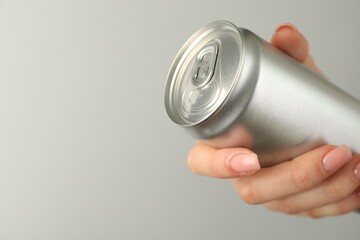 Woman with tin can on light grey background, closeup. Space for text