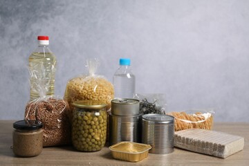 Different food products on wooden table against gray background