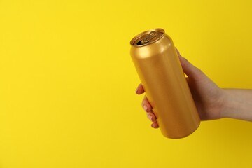 Woman with tin can on yellow background, closeup. Space for text