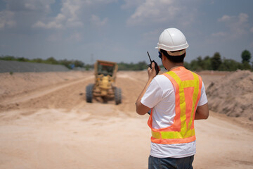 Construction Site Supervisor: A construction site supervisor, equipped with safety attire and a...