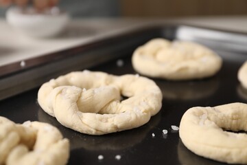 Baking tray with raw pretzels on table, closeup