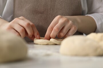 Woman shaping pretzels at table in kitchen, closeup