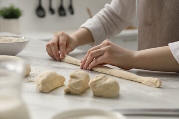 Making pretzels. Woman shaping dough at table in kitchen, closeup