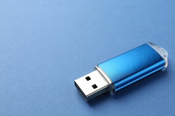 One flash drive on blue background, closeup. Space for text