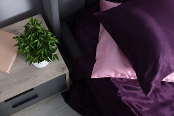 Luxury silk linens on bed and nightstand at home, above view