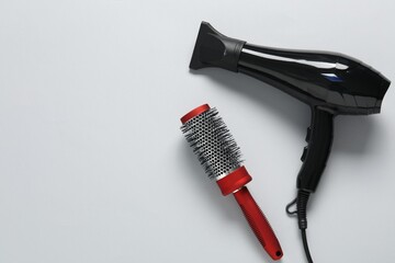 Hair dryer and brush on white background, top view. Space for text