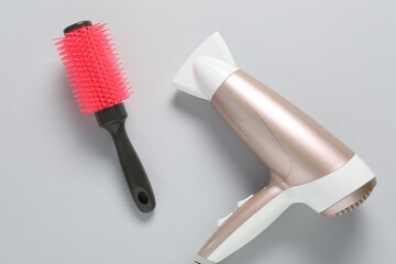 Hair dryer and brush on white background, top view