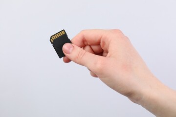Man with SD memory card on light grey background, closeup