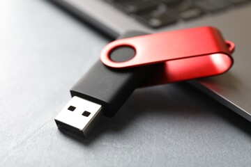 Modern flash drive and laptop on light grey table, closeup