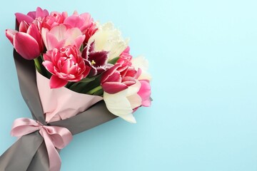 Bouquet of beautiful tulips on light blue background, top view. Space for text