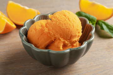 Tasty orange sorbet, fresh fruits and mint on wooden table, closeup