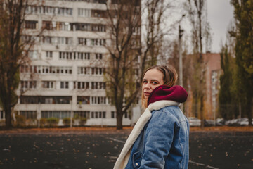 A young woman explores an urban park during an overcast day, surrounded by towering buildings and...