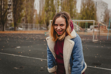 A young woman explores an urban park during an overcast day, surrounded by towering buildings and...