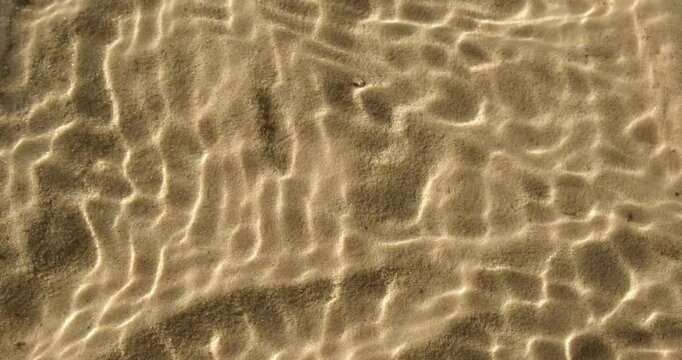 Water texture with shadows on sea beach sand