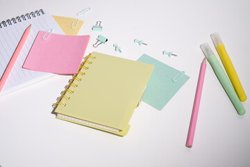 Office or school supplies. Notepad, clips, paper clips and sticky notes, pencils and markers on a colored background.