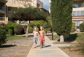 Obraz premium boys 5 - 6 years old barefoot, in shorts, cheerfully running races in the park, doing sports outdoors . concept of active games and healthy lifestyle. Who is faster. healthy lifestyle and recreation