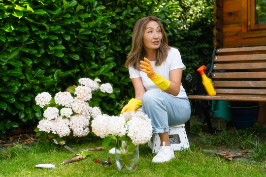 Gardener arranging flowers outdoors in a lush garden during a sunny afternoon