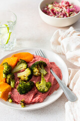 A wholesome breakfast with beet hummus, baked sweet potato, and a fresh radish and cabbage salad, rich in vitamins, fiber, and protein