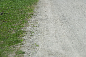 A gravel road stretches out, flanked by vibrant green grass on one side. The scene captures a tranquil rural atmosphere on a clear day, inviting leisurely travel