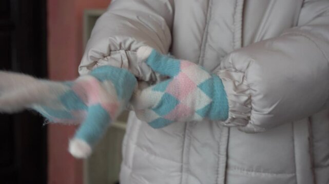 little girl putting on winter gloves, child put on warm winter gloves on her hands, fashionable woolen gloves