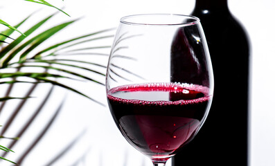 Non-alcoholic, alcohol free, red wine tempranillo in glass with bottle. White background, palm...