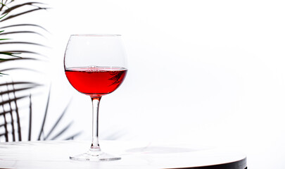 Non-alcoholic, alcohol fries,  pink rose wine grenache in glass with bottle. White background, palm leaves shadows, hard light