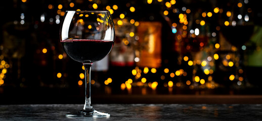 Italian dry red wine chianti glass and wine bottles on dark bar background with lights