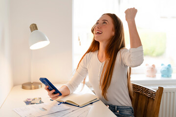 Celebrating success at home after receiving good news while checking messages on a smartphone