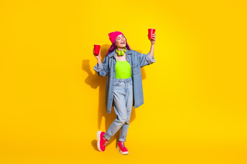 Joyful young woman in vibrant casual wear expressing cheerfulness against a bold yellow background