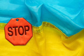 Red stop sign on blue and yellow Ukrainian flag background, concept of restriction, protest