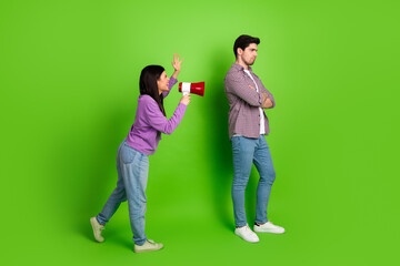 Young woman with megaphone arguing with man against green background emphasizing relationship challenges and vivid expression