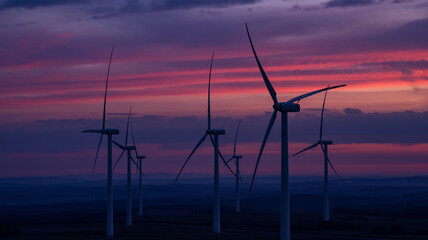 Obraz premium Wind turbines are outlined by the warm glow of the setting sun!