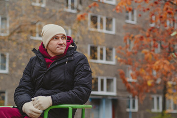 Man sitting pensively on a colorful carousel in an autumn park, contemplating life in a quiet moment