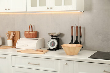 Retro mechanical kitchen scale and other utensils on white marble countertop indoors