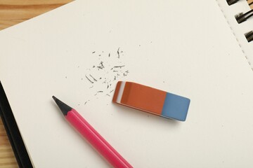 Eraser, pencil, scraps and notebook on table, top view