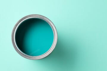 Can of bright paint on turquoise background, top view. Space for text